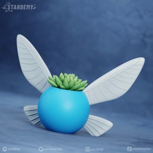 May include: A light blue planter shaped like a fairy with white wings and a green succulent plant inside.