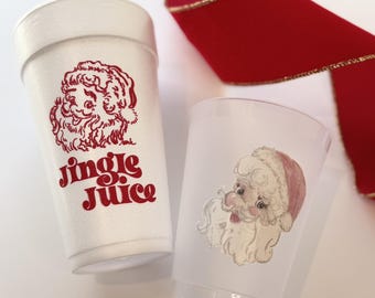 Puede incluir: Dos vasos blancos con gráficos rojos con temática navideña. Un vaso tiene las palabras "Jingle Juice" y una ilustración de Papá Noel. El otro vaso tiene una ilustración de Papá Noel. Una cinta roja con ribete dorado está en el fondo.