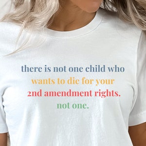 May include: White t-shirt with the text "there is not one child who wants to die for your 2nd amendment rights. not one." printed in rainbow colors.