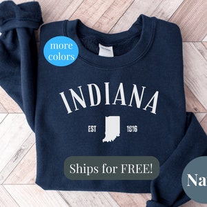 May include: Navy blue sweatshirt with white text that reads "INDIANA EST 1816" and a white outline of the state of Indiana. The sweatshirt also has the text "Ships for FREE!" in white.