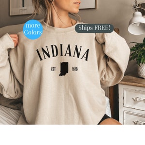 May include: A beige sweatshirt with the text "INDIANA" in black, with the state outline and "EST 1816" below.