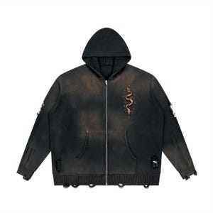May include: A black zip-up hoodie with a distressed, faded wash and frayed holes along the sleeves and hem. The front features a graphic of a coiled snake surrounded by small stars and celestial symbols on the left chest area.