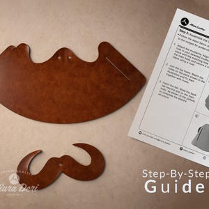 May include: Two pieces of brown leather, one large and curved, the other a mustache shape, with a step-by-step guide. The guide shows how to assemble the stand. The text on the guide says "Miura Deri" and "Step-By-Step Guide."
