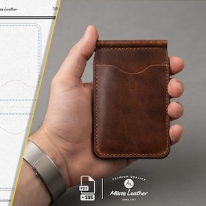 Può includere: Un portafoglio in pelle marrone con fermasoldi, uno scomparto verticale per carte e cuciture a vista. Il portafoglio presenta una finitura liscia marrone scuro e una clip metallica sulla parte superiore. Un modello tecnico è visibile a sinistra.