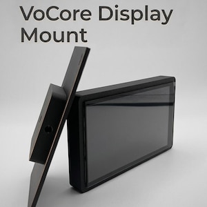 May include: A black 5-inch VoCore display mount. The mount has a rectangular screen and a supporting bracket. The text "5 Inch VoCore Display Mount" is printed on the image.