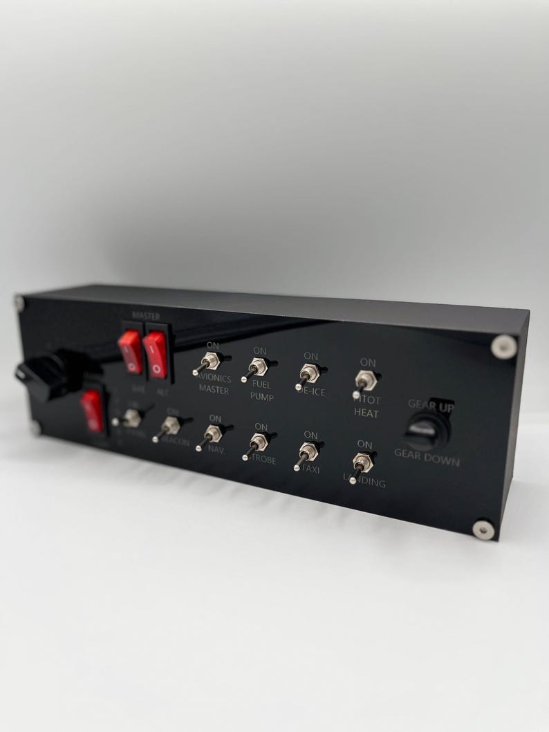 May include: A black rectangular flight simulator control panel featuring two red rocker switches, a series of metal toggle switches labeled for avionics, fuel pump, de-ice, pitot heat, beacon, nav, strobe, taxi, and landing, and a gear up/down knob.