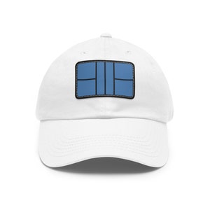 Può includere: Cappellino da baseball bianco con una toppa blu e nera che rappresenta un campo da tennis.