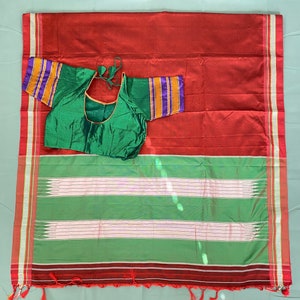 May include: A red and green saree with a white border and a green blouse. The saree has a striped pattern and the blouse has a decorative border.
