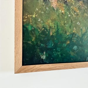 Puede incluir: Una pieza de arte mural enmarcada que presenta una pintura abstracta con tonos verde bosque profundo, esmeralda y amarillo dorado. La obra está encerrada en un marco de madera clara con veta visible, montada sobre una pared blanca lisa.
