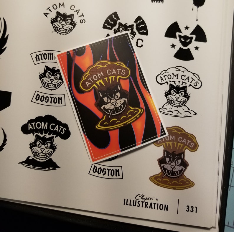 Pode incluir: Um adesivo com um gato de desenho animado com uma cabe&ccedil;a em forma de bomba. O gato est&aacute; usando uma bandana e tem uma express&atilde;o travessa. O adesivo est&aacute; em um fundo de chamas e o texto "Atom Cats" est&aacute; escrito em letras brancas.