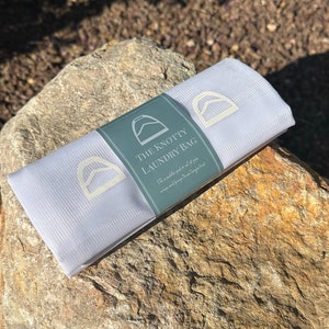May include: White mesh laundry bag with a green label that says "The Knotty Laundry Bag" and a graphic of a knotted rope. The label also says "Fits a saddle pad or set of polos, wraps and keeps them tangle free."