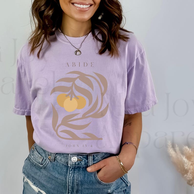 May include: A lavender t-shirt with a graphic of a branch with two yellow oranges and the text "ABIDE JOHN 15:4".