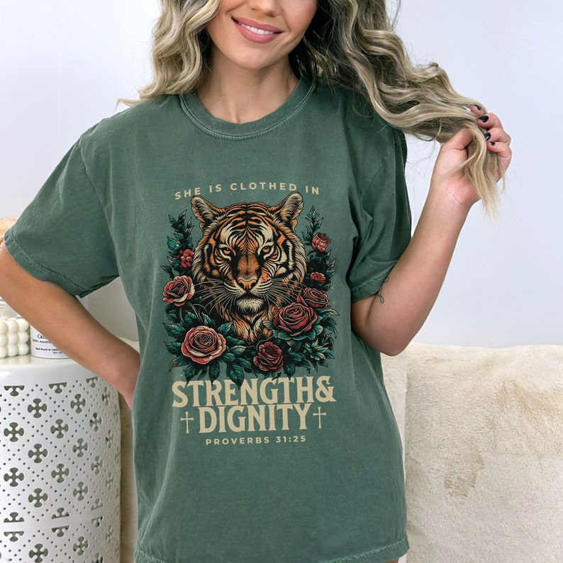 May include: Green t-shirt with a tiger graphic and the text "She is clothed in strength & dignity + Proverbs 31:25"