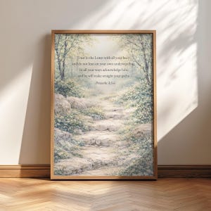 Könnte beinhalten: Ein gerahmter Druck mit einer ruhigen Landschaft mit einem Steinweg, der durch einen Wald führt. Das Kunstwerk enthält den Text "Trust in the LORD with all your heart... Proverbs 3:5-6" in einer klassischen Schriftart.