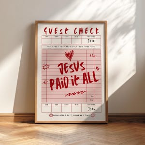 May include: A framed print resembling a guest check, featuring red text and a pink grid background. The words "GUEST CHECK" are at the top, with "J316" as the check number. The phrase "JESUS PAID IT ALL" is prominently displayed, along with a heart and other doodles.