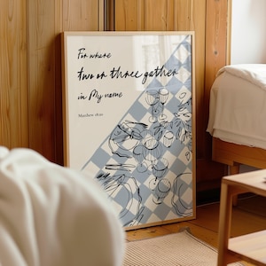 May include: A framed wall art print featuring a light blue and white checkered pattern background with black line art illustrations of wine glasses and plates. The text reads: For where two or three gather in My name Matthew 18:20.