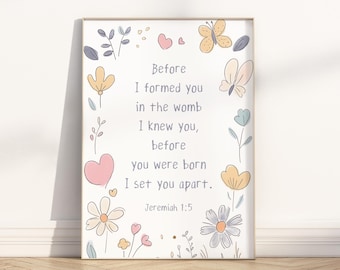 May include: A framed print with a light background, featuring the text "Before I formed you in the womb I knew you, before you were born I set you apart. Jeremiah 1:5." The print is decorated with pastel-colored flowers, butterflies, and hearts.