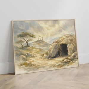 Op de afbeelding: Aquarel schilderij van een landschap met een pad dat naar een graf leidt. Drie kruisen staan op een verre heuvel. Het kunstwerk heeft een neutraal kleurenpalet met een focus op licht en schaduw, ingelijst in een licht houten frame.