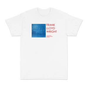 Könnte beinhalten: Weißes T-Shirt mit einem blauen und weißen Bauplan-Design eines Hauses. Der Text "FRANK LLOYD WRIGHT" ist in Rot über dem Bauplan gedruckt. Der Text "TALIESIN WEST, ARIZONA, JULY 1938" ist in kleinerer roter Schrift unter dem Bauplan gedruckt.