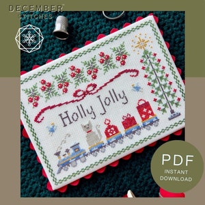 May include: A rectangular cross-stitch pattern on white fabric featuring the text Holly Jolly, a train with a cat passenger, gift-wrapped presents, a Christmas tree, and holly sprigs. The design is bordered by a green stitched frame.