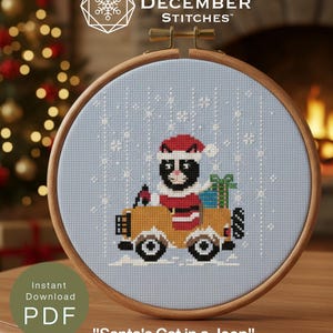 May include: A cross-stitch pattern in a wooden hoop featuring a black and white cat wearing a red Santa hat and coat, driving a yellow jeep with a green gift box in the back. The light blue fabric background includes white stitched snowflakes.