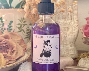 May include: A glass bottle with a dropper top filled with a purple liquid. The label reads "The Green Maenad Samhain Oil rebirth * darkness * wisdom". The label also features a witch's cauldron, broom, and crescent moons.