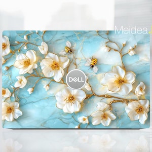 May include: A blue and white laptop skin with a floral design featuring white flowers with gold accents and bees. The Dell logo is visible on the skin.