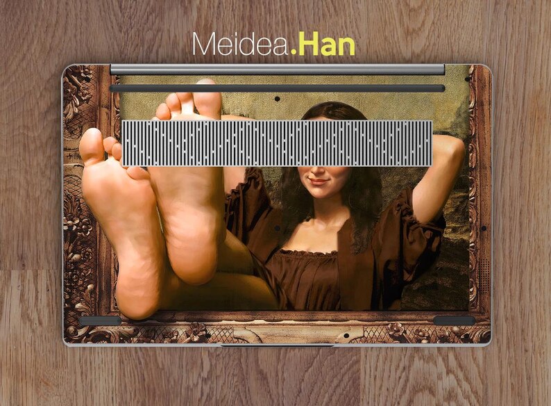 May include: A laptop skin with a painting of a woman in a brown dress with her feet sticking out of the frame. The painting is in a gold frame and the text "Meidea.Han" is at the top of the image.