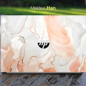 Könnte beinhalten: Laptop-Skin mit abstraktem Design in Weiß, Pfirsich und Grau. Das HP-Logo befindet sich unten rechts. Der Text "Meidea.Han" ist oben links. Das Design hat einen fließenden, marmorierten Effekt.