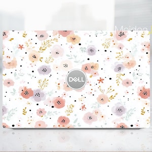 May include: A white laptop skin featuring a floral pattern with pink, peach, and lavender flowers, accented by gold leaves and black dots. The Dell logo is centered. The design covers the entire top surface of the laptop.