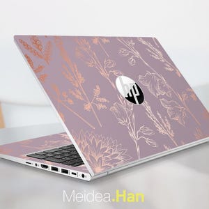 Könnte beinhalten: Ein lila HP-Laptop mit einem roségoldenen Blumendesign. Der Laptop ist geöffnet und zeigt die Tastatur und den Bildschirm. Das HP-Logo ist auf dem Deckel sichtbar. Der Text "Meidea.Han" befindet sich unten.