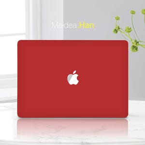 Puede incluir: Un portátil rojo con el logotipo blanco de Apple. El portátil es de color rojo sólido y vibrante. El texto "Meidea.Han" está en la esquina superior izquierda. El fondo es de color gris claro.