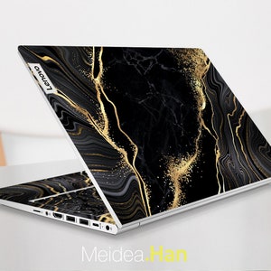 Puede incluir: Port&aacute;til negro con un dise&ntilde;o de m&aacute;rmol dorado y negro. El port&aacute;til tiene el logotipo de Lenovo en la parte posterior.