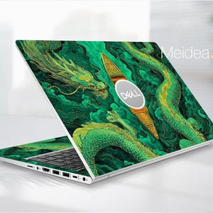 Può includere: Un laptop Dell con un vivace design a drago verde e oro. L'opera d'arte copre il coperchio e la base, con un'illustrazione dettagliata di un drago tra nuvole vorticose. Il testo "Meidea.Han" è visibile sul laptop.