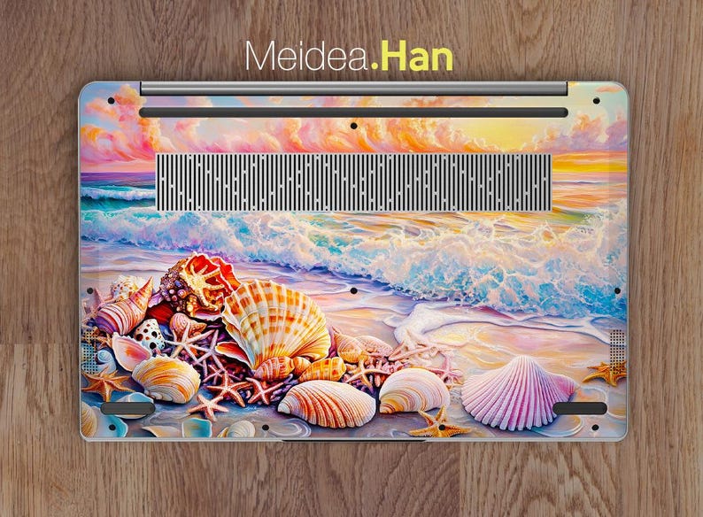 Op de afbeelding: Een laptop skin met een kleurrijk schelpdesign. De skin toont een zonsondergang boven de oceaan met golven die op de kust breken. De schelpen zijn in tinten roze, wit en bruin.