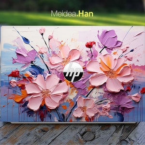 May include: A white laptop with a floral design on the lid. The design features pink, purple, and orange flowers with a blue background. The HP logo is visible in the centre of the lid.