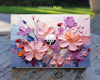 May include: A white laptop with a floral design on the lid. The design features pink, purple, and orange flowers with a blue background. The HP logo is visible in the center of the lid.
