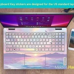 Pu&ograve; includere: Un computer portatile con un adesivo per tastiera che raffigura un tramonto su uno specchio d'acqua. L'adesivo &egrave; progettato per una tastiera standard americana. Il computer portatile &egrave; del marchio Lenovo.