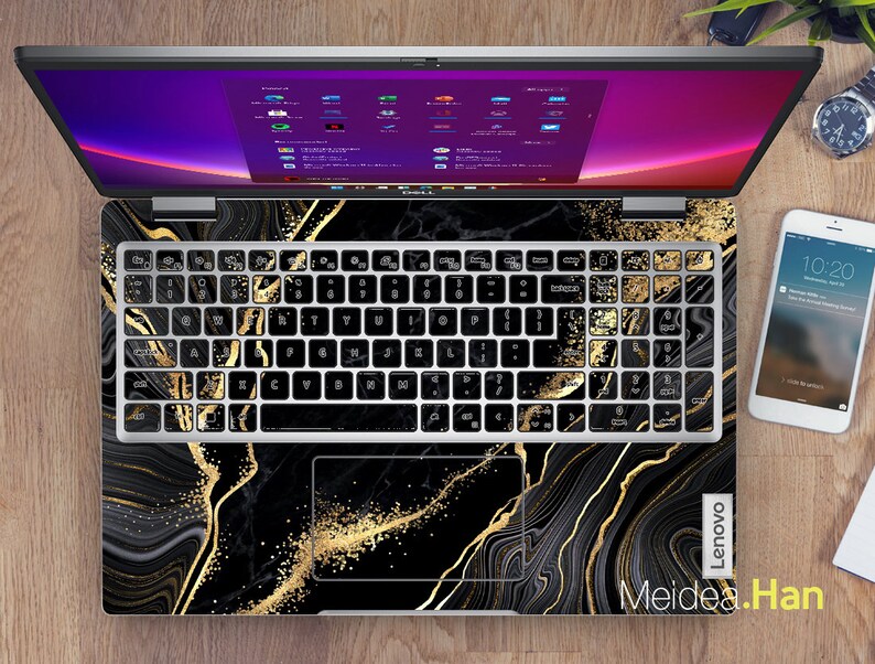 Puede incluir: Un port&aacute;til negro con un dise&ntilde;o de m&aacute;rmol dorado y negro en el teclado y el touchpad. La pantalla del port&aacute;til est&aacute; encendida y muestra un escritorio con varias ventanas abiertas. El port&aacute;til tiene el logotipo de Lenovo en la esquina inferior derecha. El texto "Meidea.Han" est&aacute; en la esquina inferior izquierda.