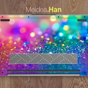 May include: A laptop with a colorful glitter and bokeh background. The laptop has a silver finish and a black vent.