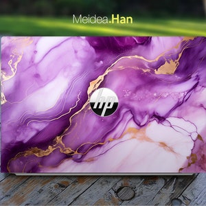 Könnte beinhalten: Lila und goldene Marmor-Laptop-Haut mit dem HP-Logo in der Mitte.