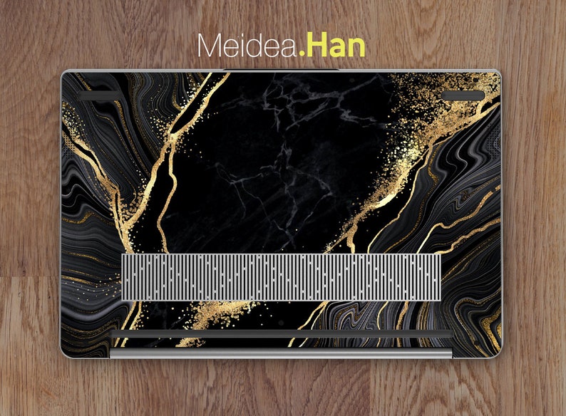 Puede incluir: Port&aacute;til negro con una piel de dise&ntilde;o de m&aacute;rmol dorado y negro. La piel tiene un patr&oacute;n de remolino con detalles dorados y un sutil efecto de brillo.