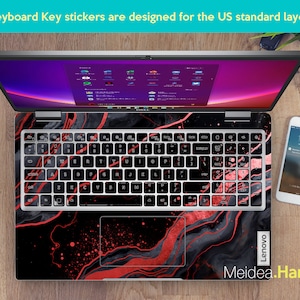 K&ouml;nnte beinhalten: Laptop mit einer Tastaturfolie mit einem schwarzen und roten Marmormuster. Die Tastaturtasten sind schwarz mit wei&szlig;er Beschriftung und roten Akzenten. Der Text "Keyboard Key stickers are designed for the US standard layout" ist sichtbar.