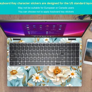 Puede incluir: Un ordenador port&aacute;til con una pegatina de teclado floral. La pegatina presenta flores blancas sobre un fondo azul claro. El port&aacute;til est&aacute; abierto y la pantalla muestra un escritorio con iconos. El texto en la pegatina dice "Keyboard Key character stickers are designed for the US standard layout. May not be suitable for European or Canada users. You can choose not to apply keyboard key stickers."