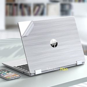 May include: A silver laptop with a brushed metal finish and the HP logo on the lid. The laptop is closed and has a protective film on the lid.