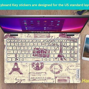 May include: A laptop keyboard with a vintage travel themed sticker set. The stickers feature images of the Eiffel Tower, stamps, and other travel-related designs. The text "Keyboard Key stickers are designed for the US standard layout" is visible at the top of the image.