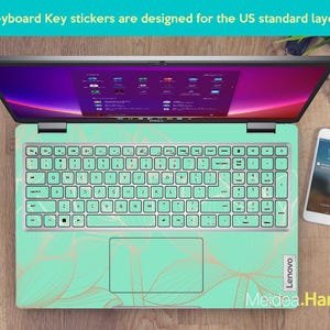 May include: A laptop computer with a green and gold keyboard sticker featuring a leaf design. The sticker is designed for the US standard keyboard layout. The text "Lenovo" and "Meidea.Han" are visible on the sticker.