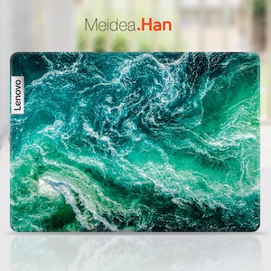 May include: A laptop computer with a green and blue ocean wave design on the back. The laptop has a Lenovo logo on the left side.