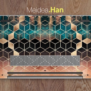 May include: A laptop with a geometric pattern on the back. The pattern is made up of gold and teal cubes on a black background. The laptop is on a wooden surface.