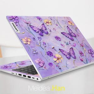 May include: A purple laptop with a floral design featuring butterflies and flowers. The laptop has a silver Lenovo logo on the lid.